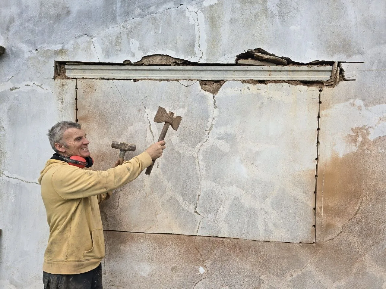 Steven opening up an old wall with an axe and a hammer