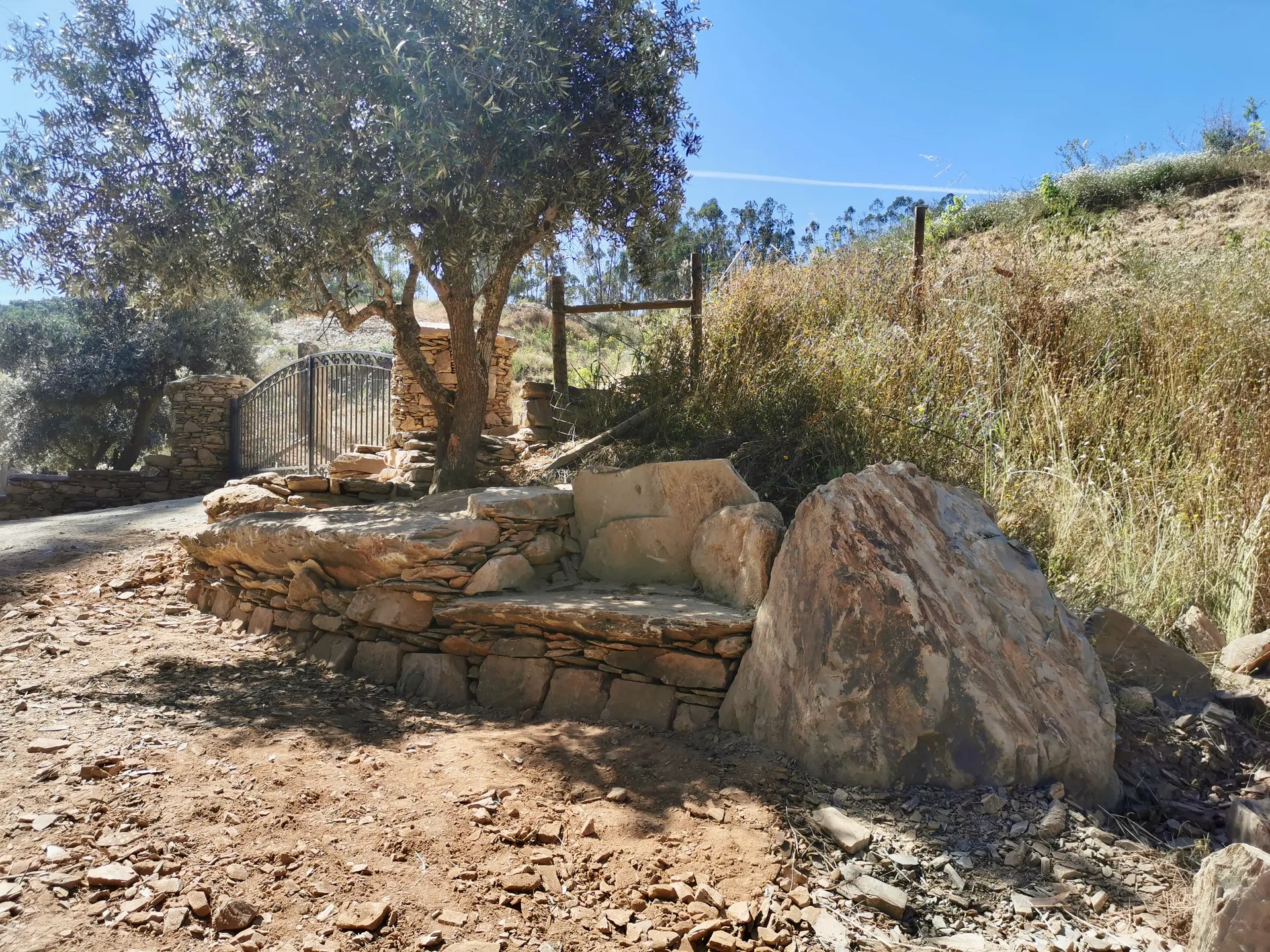 Dry stone bench with large seat slabs under olives