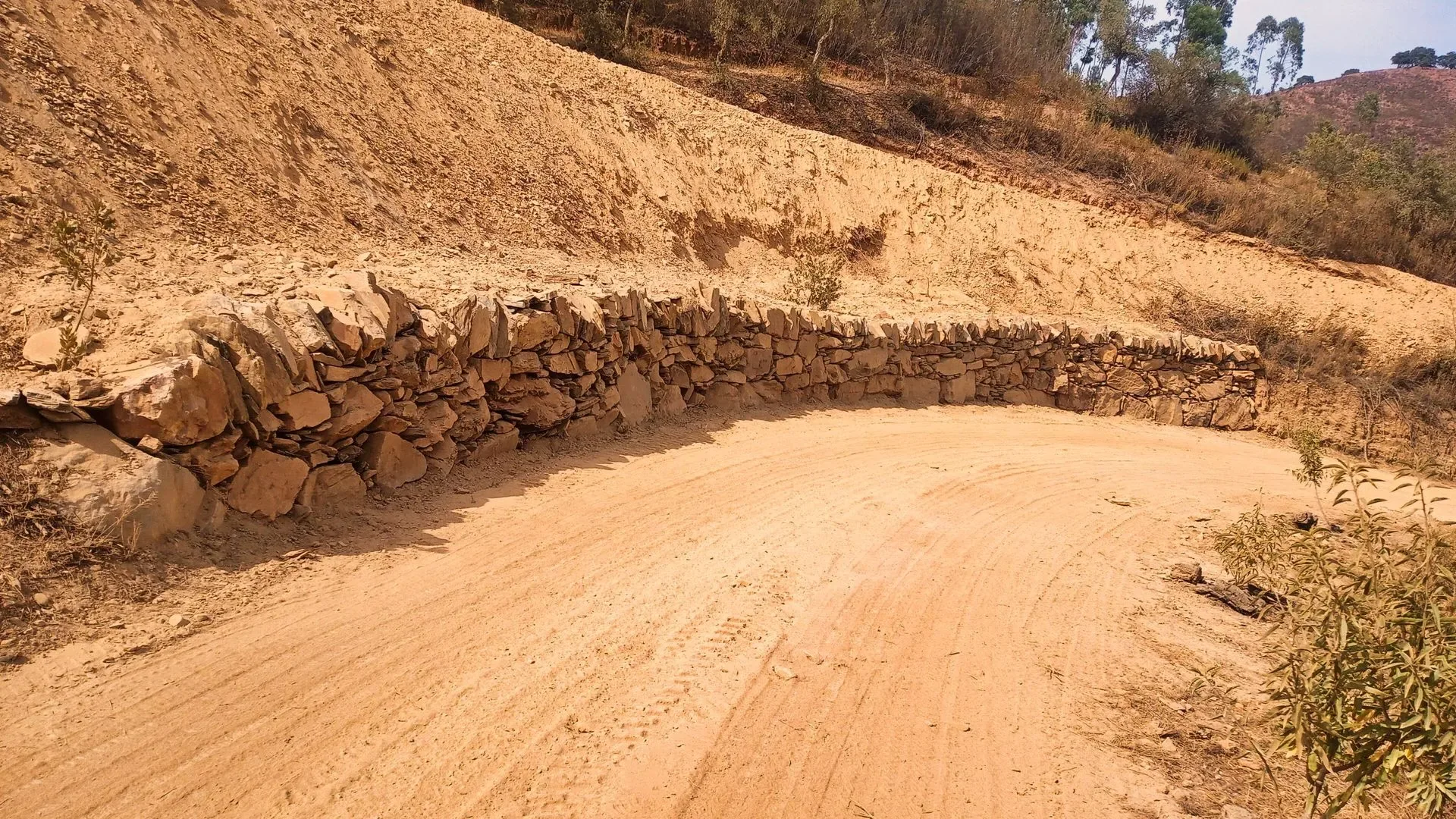 Dry stone retaining wall curving along a hillside track