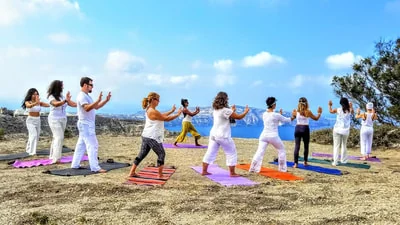A qigong group dressed in white on a cliff top above the sea