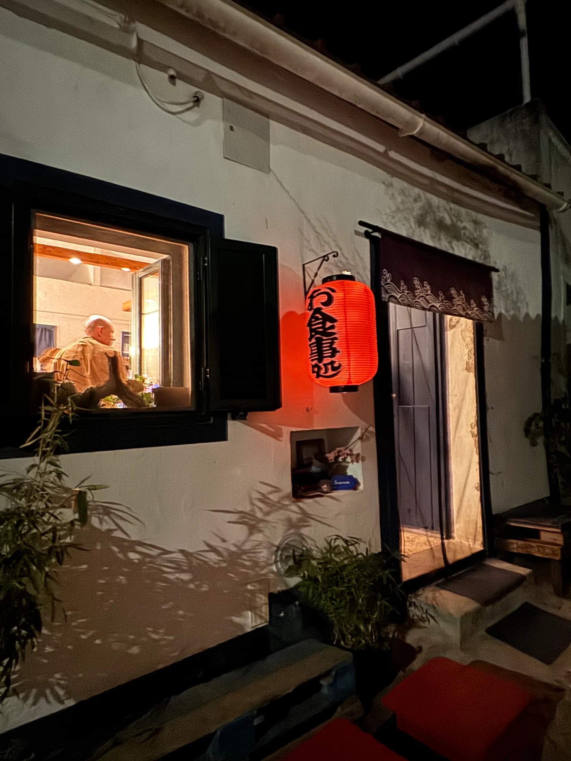 The door of SAZANAMI at night, with a red paper lantern and a curtain